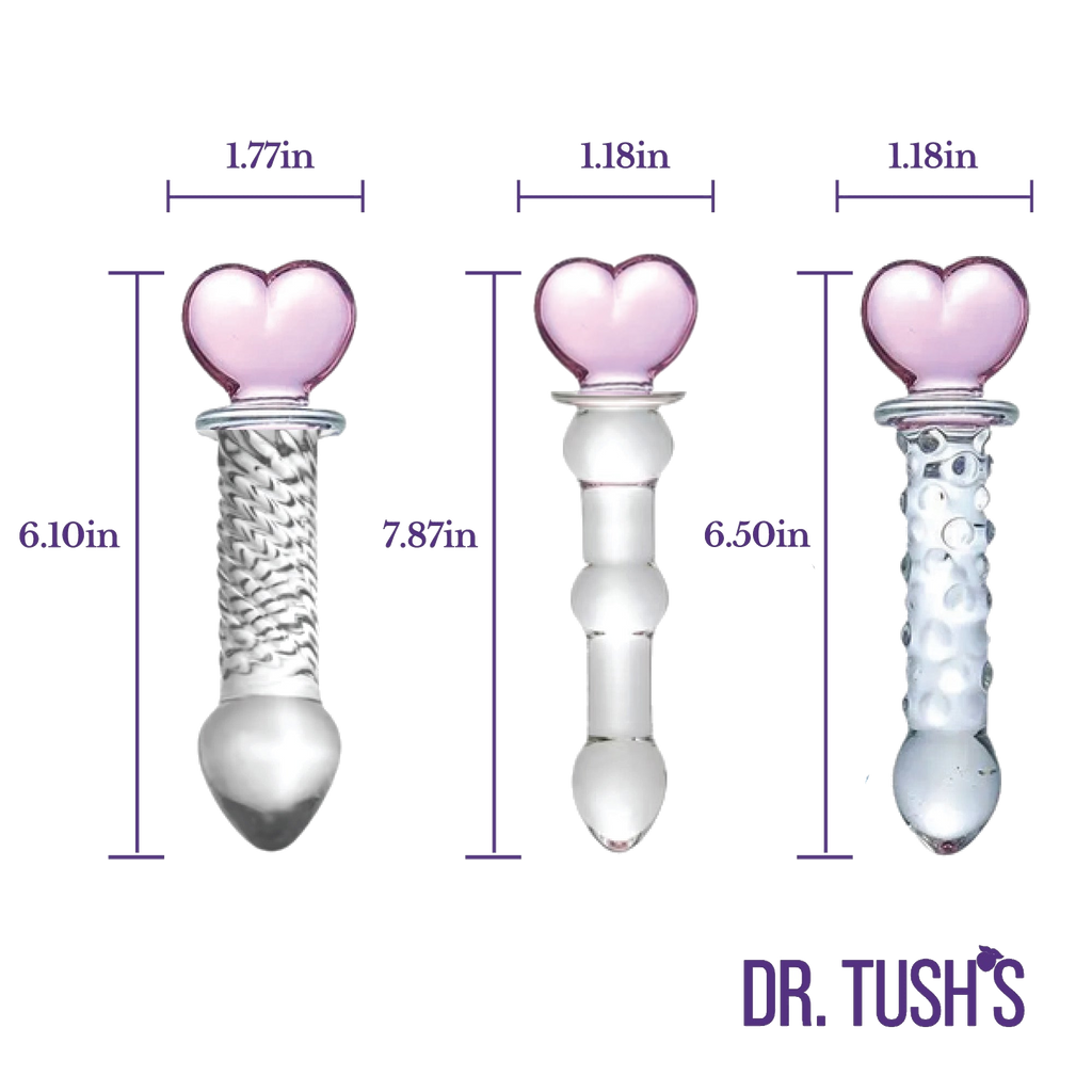 Three glass butt plugs with heart shaped top and glass dildo with pink heart top showing measurements and clear design on a white background, branded 'Dr. Tush'.