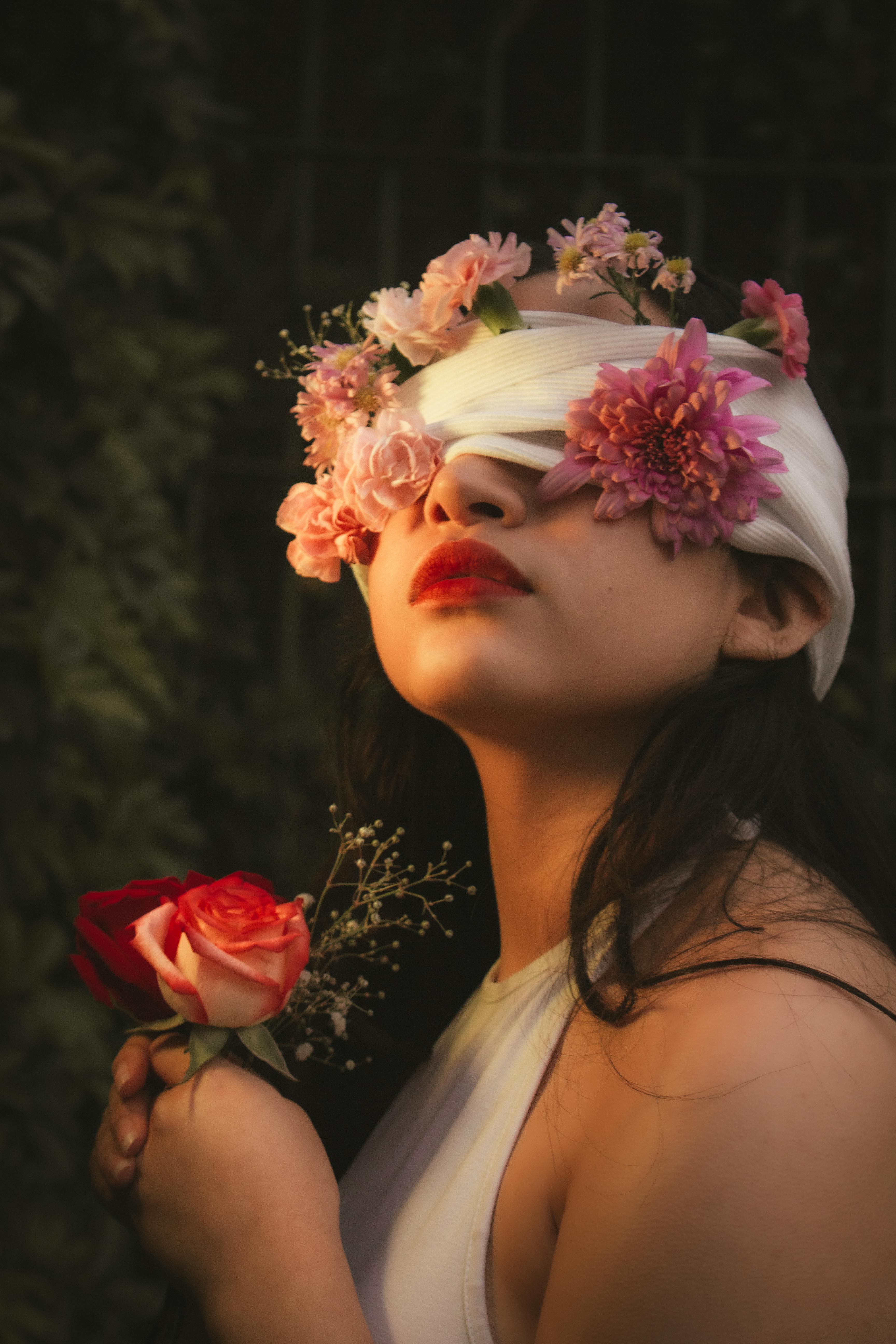 Woman with flowers in her hair holding a red rose against a dark background